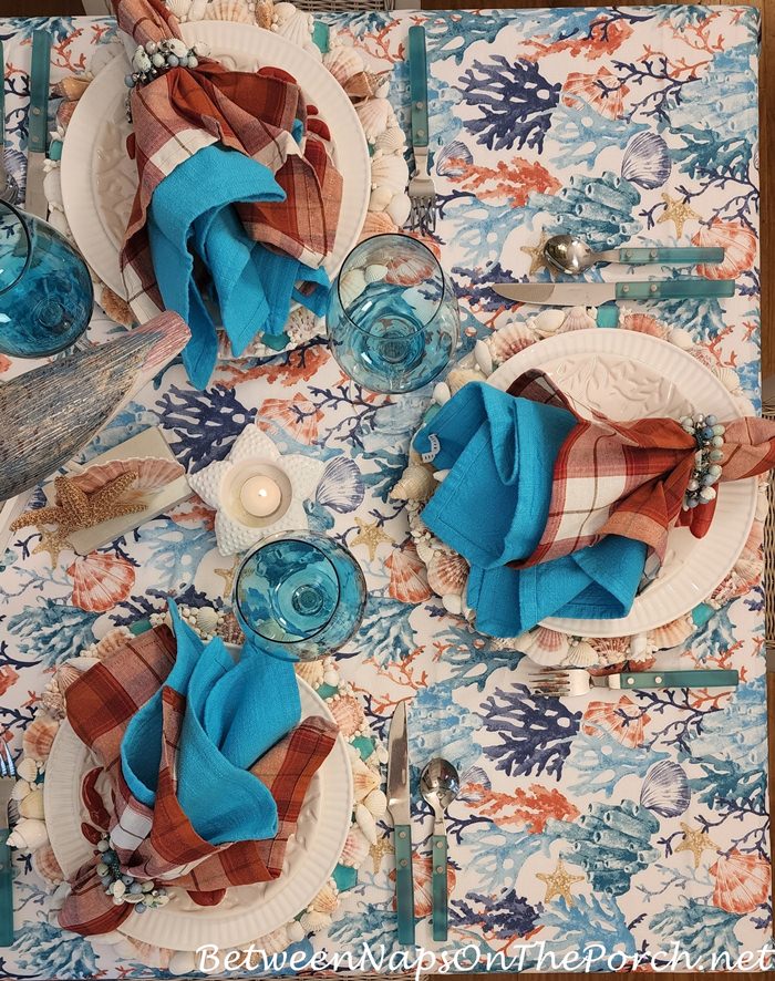 Seaside Table Setting with Blue Flatware and Coral Shell Tablecloth